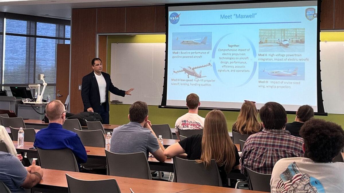 A man stands in front of a classroom giving a presentation on NASA's 