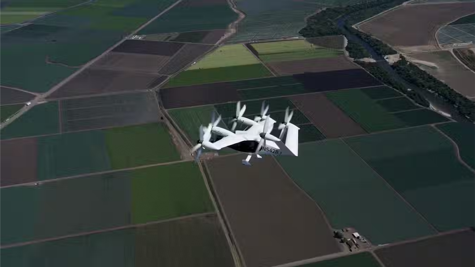 A Joby S4 flies over a patchwork of green and brown agricultural fields.