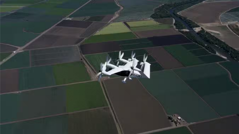 A Joby S4 flies over a patchwork of green and brown agricultural fields.
