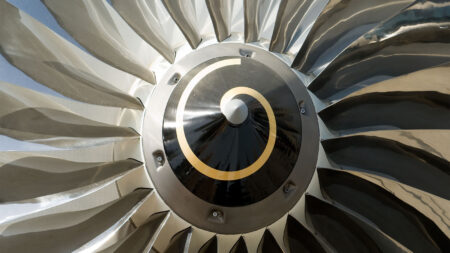 Close-up of a jet engine turbine with metallic blades and a spiral pattern at the center.