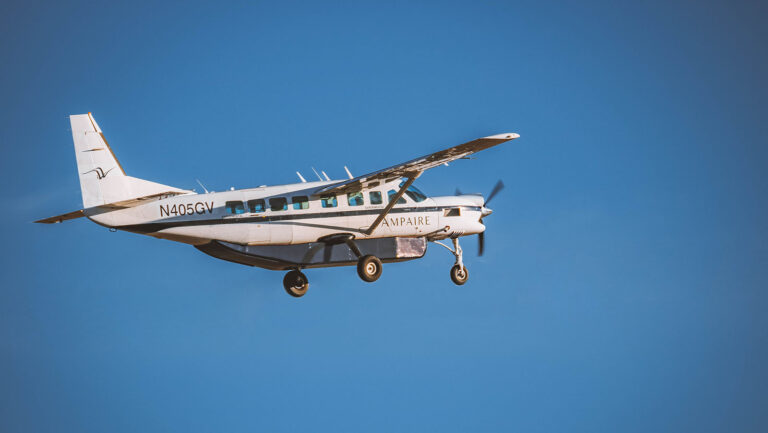 A small airplane with "Ampaire" on the side and registration N409GV flies against a clear blue sky.