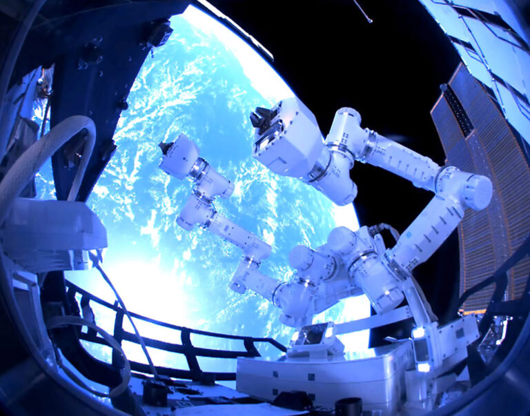 A robotic arm is seen operating on the International Space Station with a view of Earth in the background.