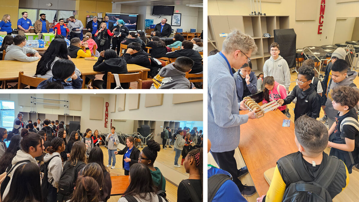 A group of students and adults engage in discussions and activities in a classroom setting, featuring multiple tables and educational materials.